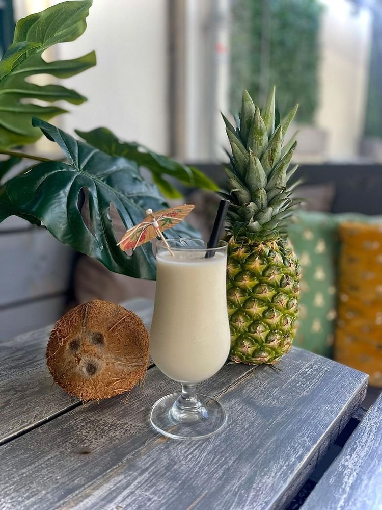 Piña colada naast een ananas en kokosnoot